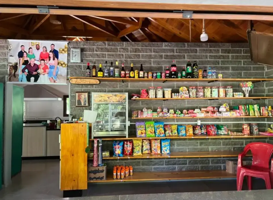 Balcão do bar com prateleiras de bebidas, doces e salgadinhos
