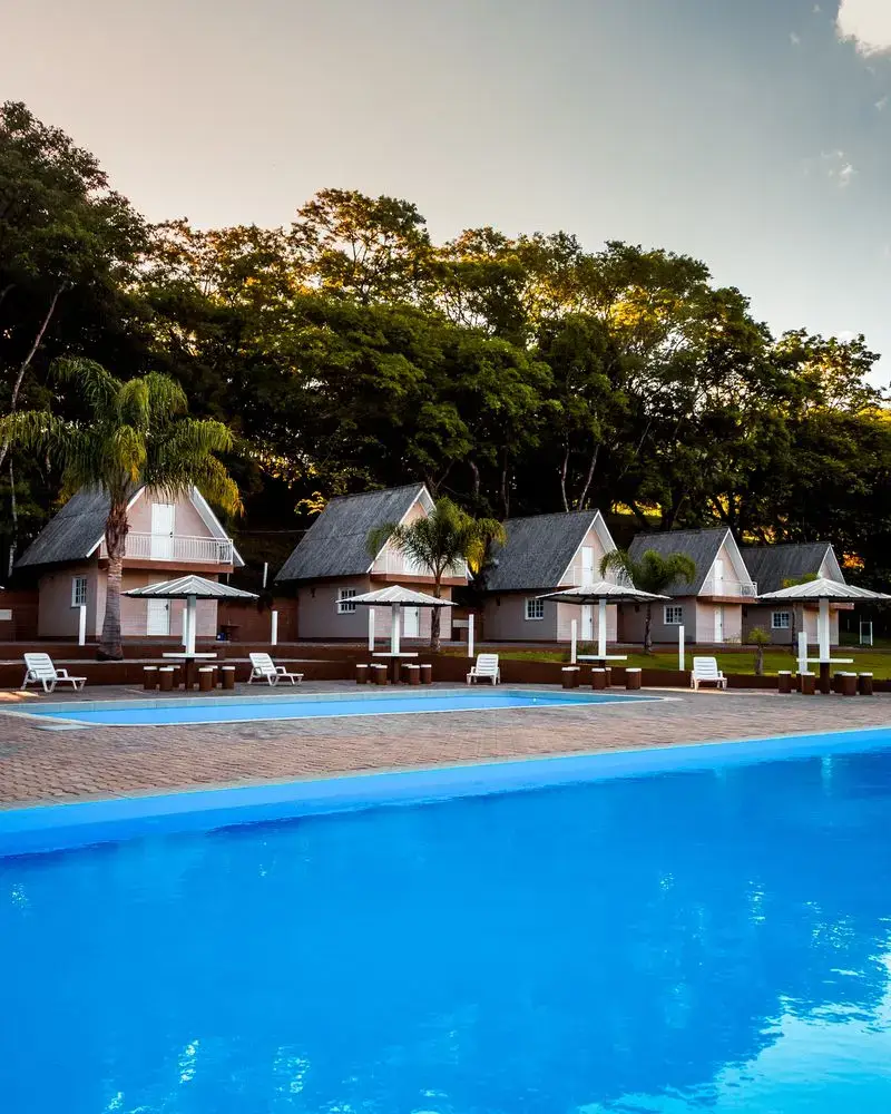 Cabanas em estilo chalé atrás da piscina, no fim da tarde