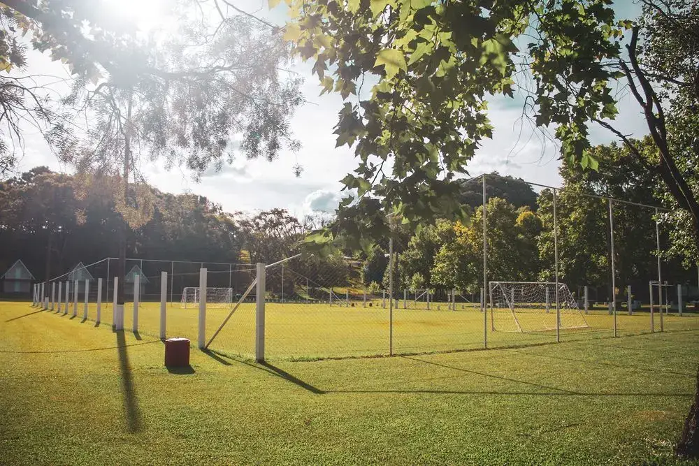 Campo de futebol com redes de proteção, à luz do sol da tarde