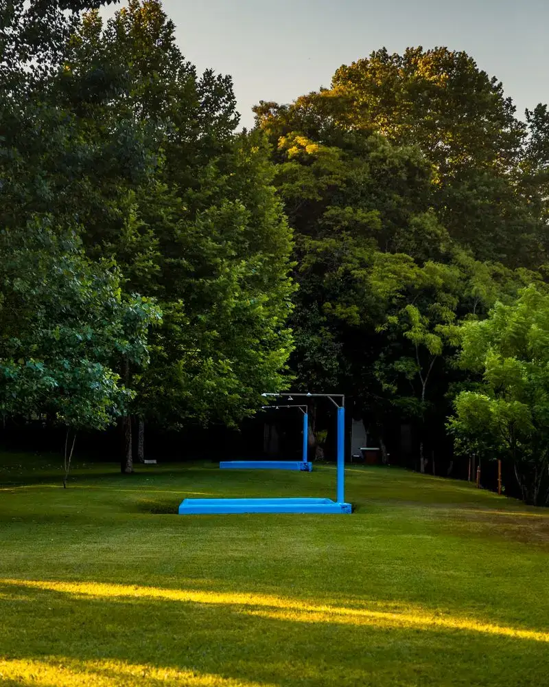 Piscina infantil rasa com chuveiro, no gramado ao pé da mata